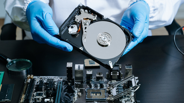 Person with gloves holding a computer hard drive