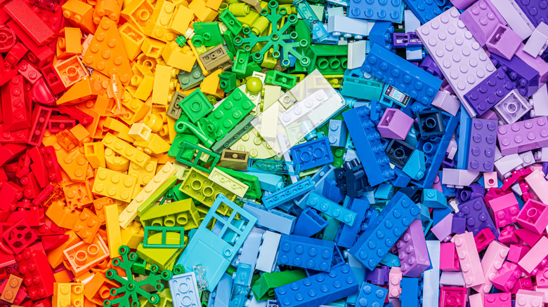 A pile of LEGO-style bricks arranged by color from red to pink