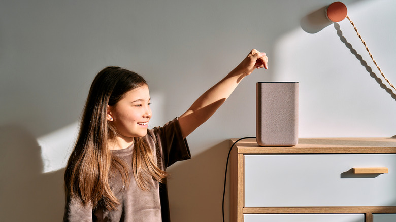 A kid smiling as they interact with the Amazon Echo speaker on top of a dresser