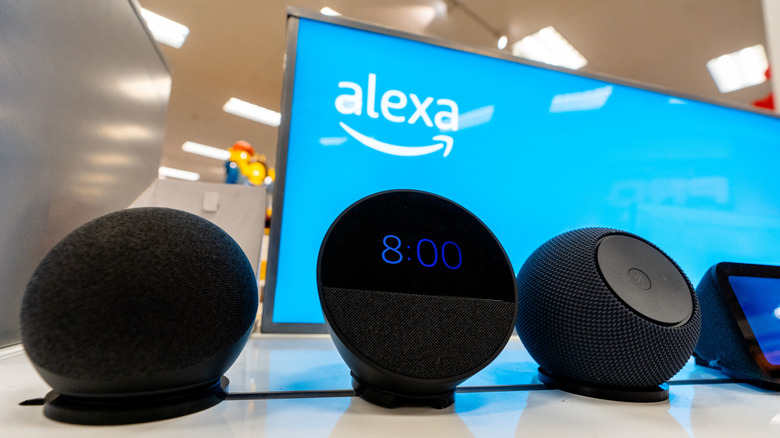 A lineup of Amazon Alexa devices in front of the Alexa logo on a display screen