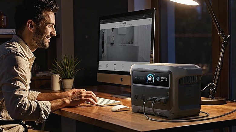 Man working on a PC powered by an Anker power station.