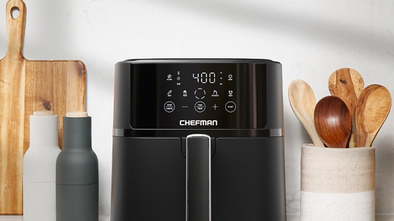 Black Chefman air fryer placed alongside kitchen utensils.