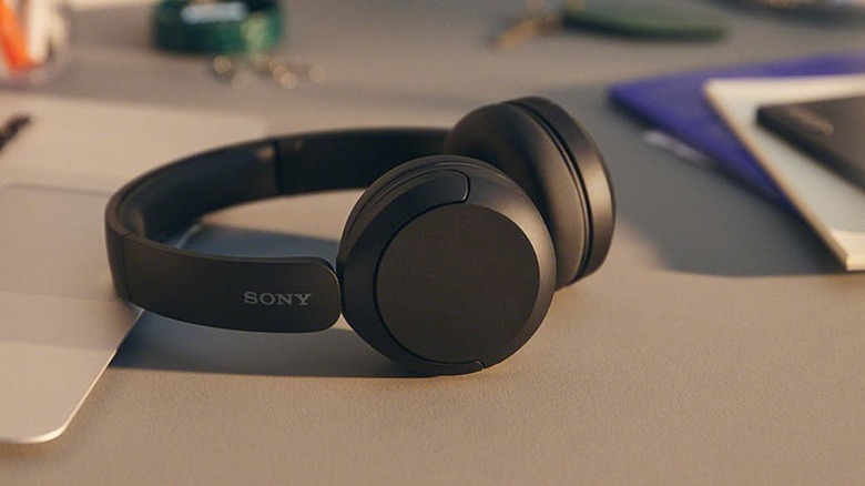 Black Sony wireless headphones beside a laptop.