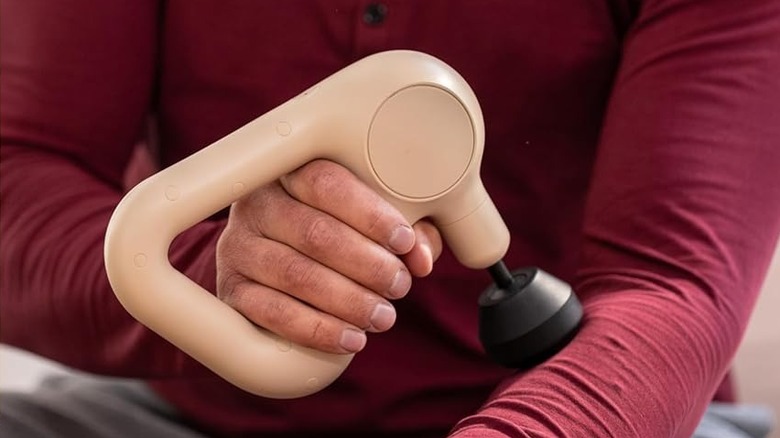 A person using the TheraGun Relief massage gun on their arm.