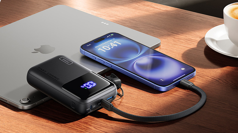 The INIU Cougar P62-E1 power bank charging an iPhone on a table.