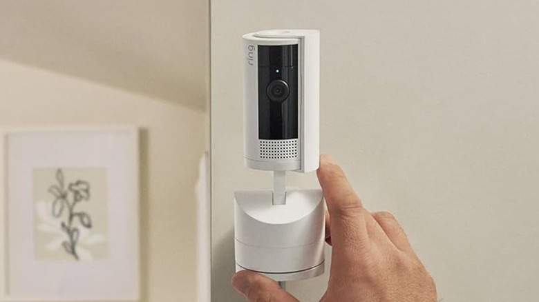 A person installing the Ring Pan-Tilt Indoor Cam security camera on a wall.