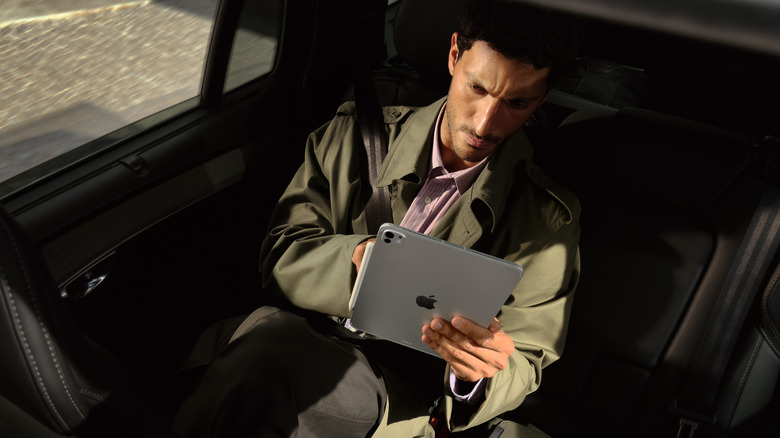 Person using iPad Pro while seated in the back of a car