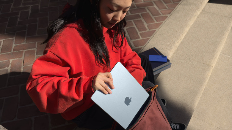 Woman placing a MacBook Air into a backpack outdoors