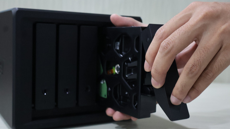 A personal installing a hard drive into a Network Attached Storage system