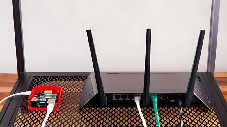 An image of a raspberry Pi enclosed in a red case and connected to a router via Ethernet