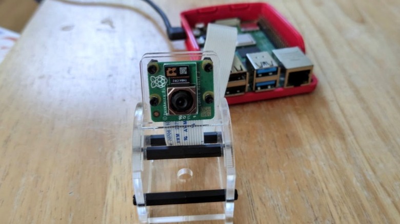 An image of a Raspberry Pi camera module stood on a DIY stand connected to a Raspberry Pi