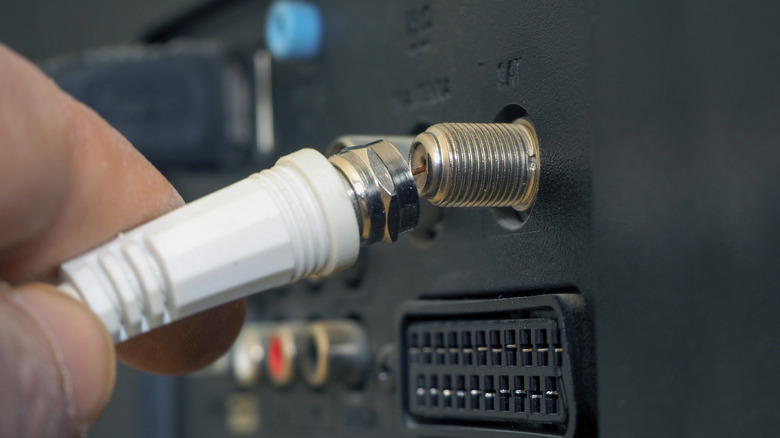 A person connecting a coaxial cable for a TV antenna