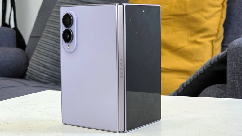 A two-tone gray Samsung Galaxy Z Fold 8 placed on a table in front of a gray sofa.