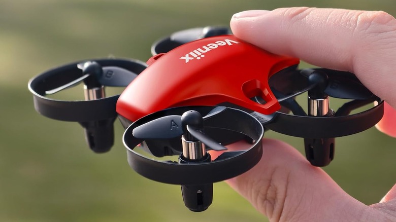 A hand holding a red Veenix V995 Mini drone