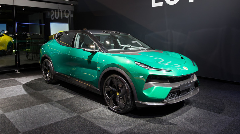 A bright green Lotus Eletre electric SUV displayed indoors at an auto show under exhibition lighting.