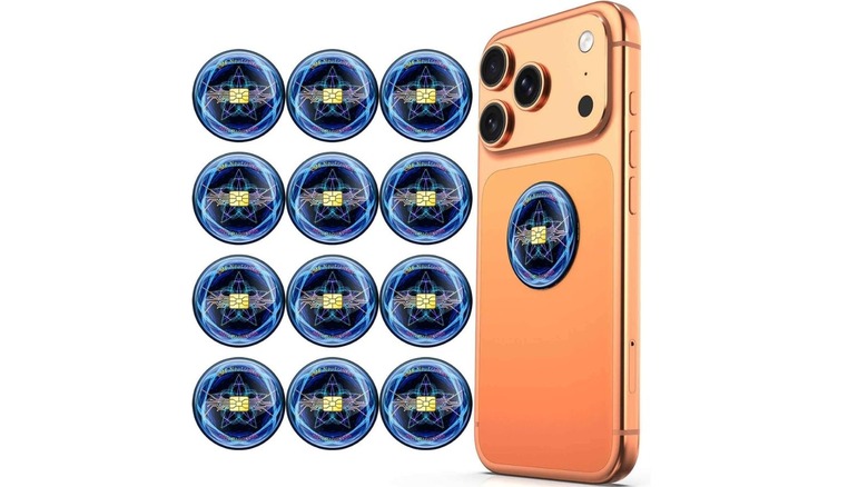 An iPhone 17 Pro with a number of stickers beside it; there's one sticker on its back as well