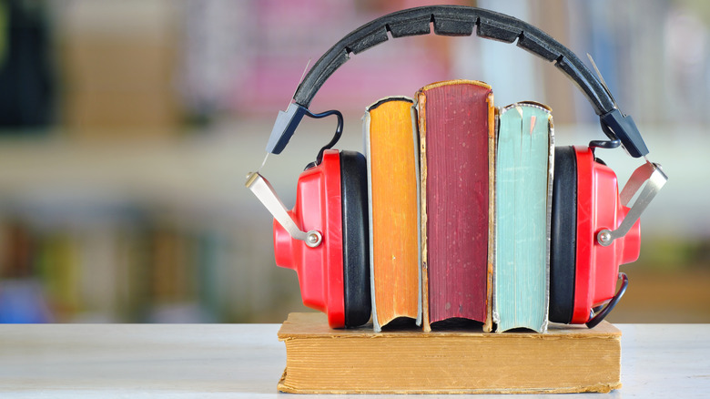 A row of books with their spines up, straddled by some headphones like bookends.