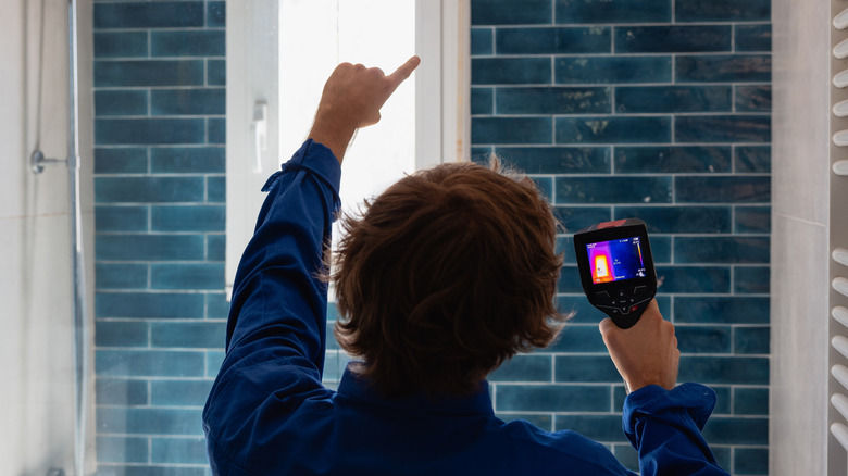 A person using a thermal camera to detect water leaks in the bathroom.