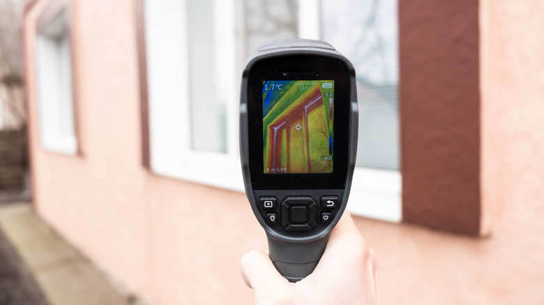 A person using a thermal camera to check for heat loss from windows.