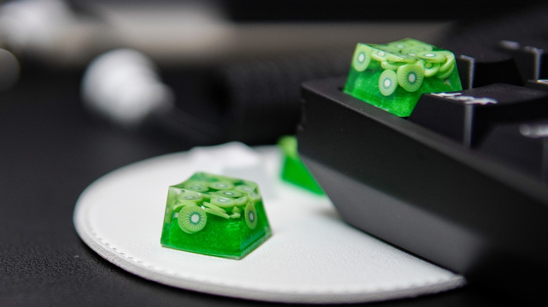 A close up photo of customized key caps that look like slices of kiwi.