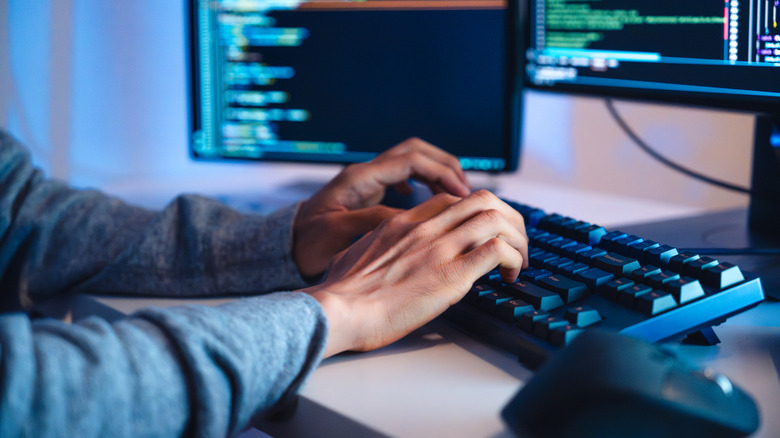 A pair of hands are typing at a computer keyboard at a desk.