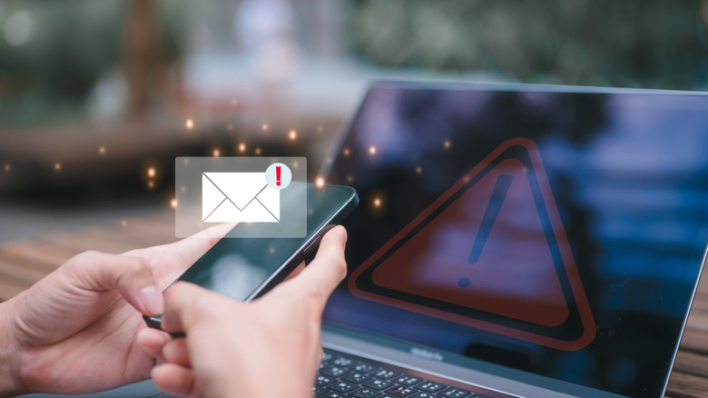 A person using a smartphone and laptop with security warnings