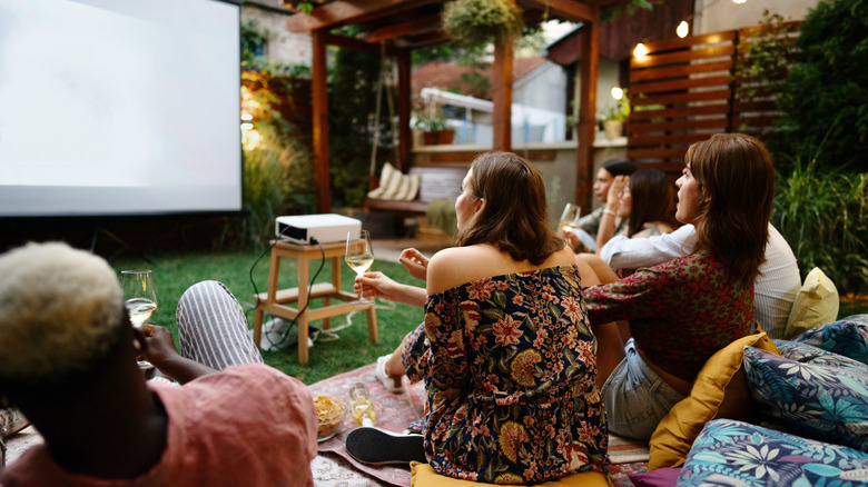 A group of friends having an outdoor movie night in early evening; screen is barely visible