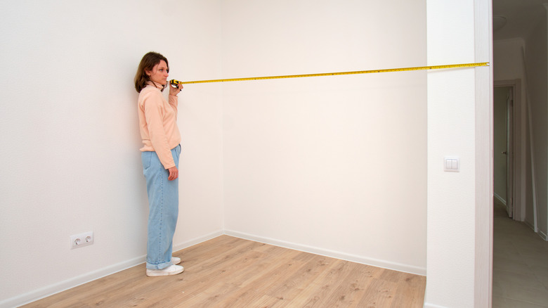 Woman measuring an empty room