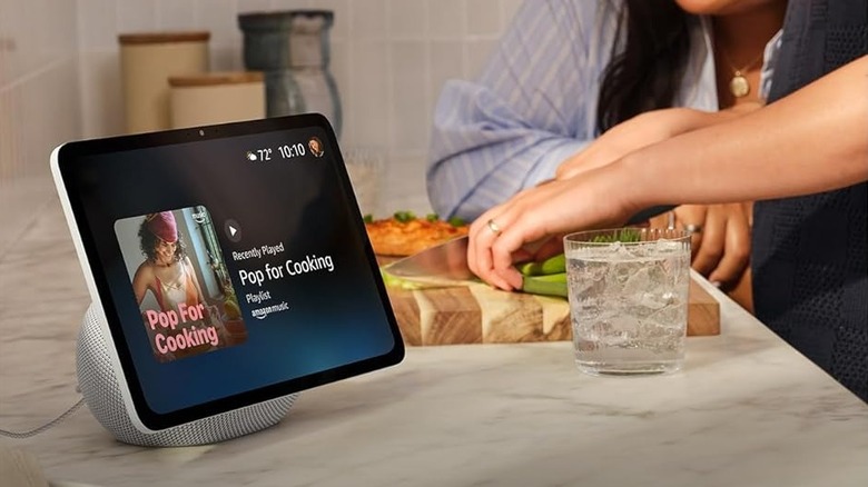 The Amazon Echo Show 11 smart display on a kitchen counter while a person is slicing vegetables.
