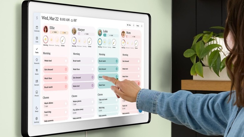A person using the Skylight Calendar Max, mounted on a wall.