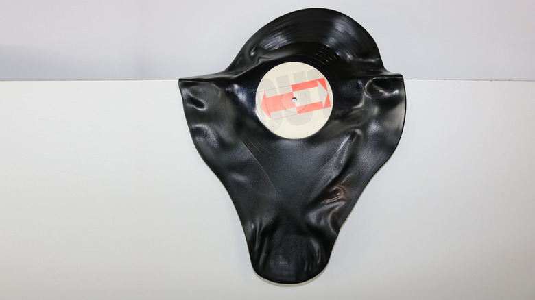 Warped vinyl record with severe heat damage, showing the disc distorted and misshapen against a plain white background.