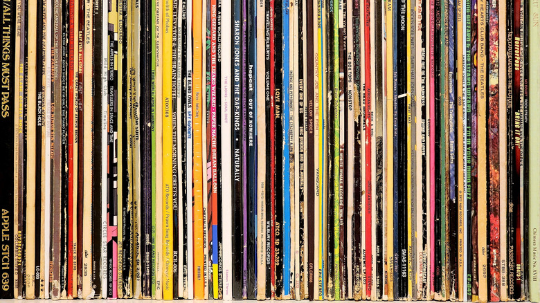 Collection of vinyl records stored upright on a shelf, showing the colorful album spines of numerous LPs arranged side by side.