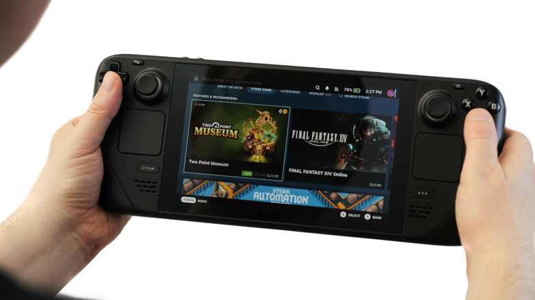 Person holding a Steam Deck handheld gaming PC displaying the Steam Store interface, with both thumbs on the controls against a white background.
