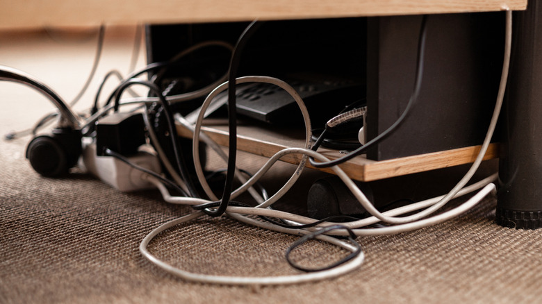 A close up photo of a mess of computer cables under a desk