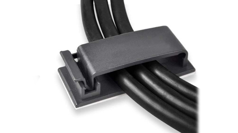 A close up of a flat cable management clip holding three cables