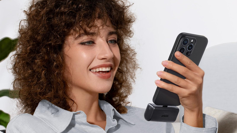 A person using their phone, with the Anker portable charger attached to it