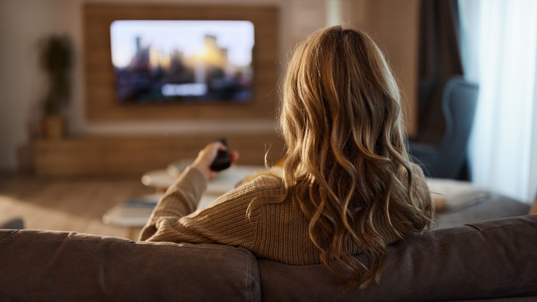 A person sitting on a couch, looking at their TV in the living room