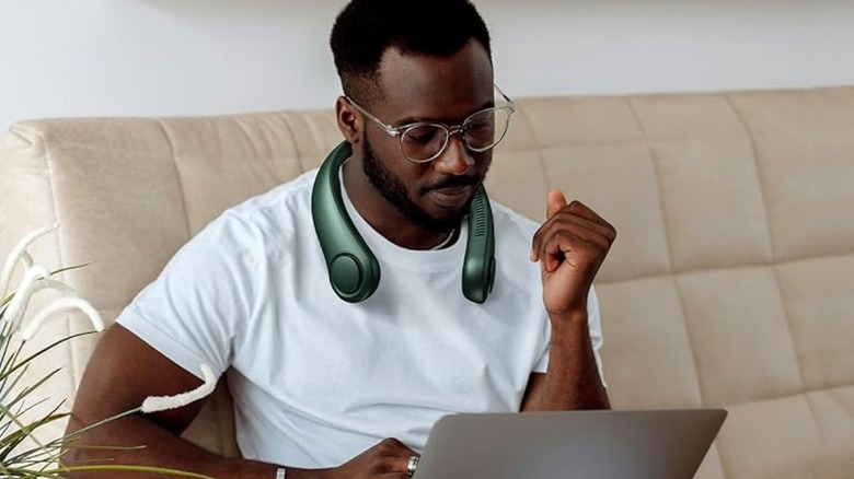 A person using the Jisulife Neck Fan Life3 while on the couch.