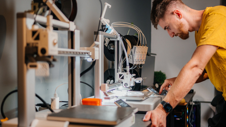 A man adjusts one of his 3D printers