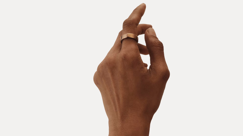A person's left hand wearing an Oura ring on their index finger.