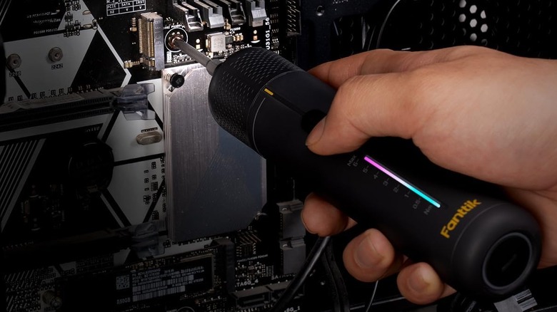 A person using the Fanttik NEX S2 Pro Electric Screwdriver on a computer motherboard.