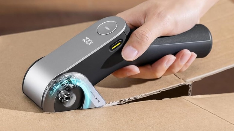 A person using the Hoto EdgeFlow Cordless Electric Scissors to cut a cardboard box.