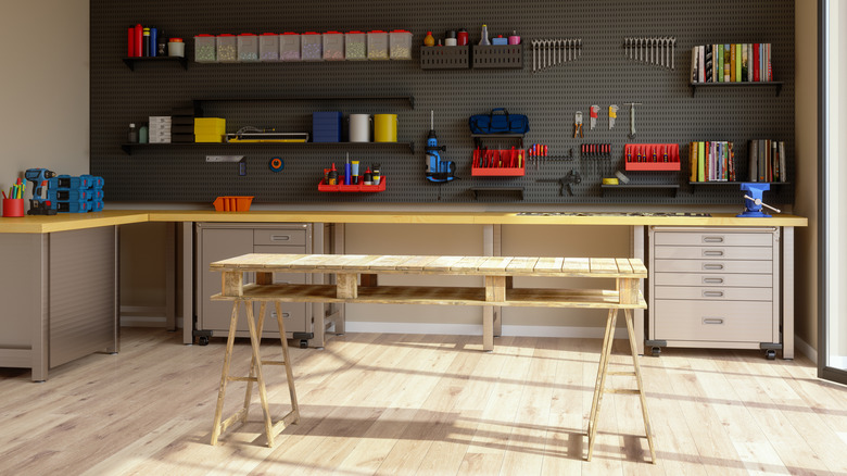 A workshop with a table in the middle and tools on shelves in the background.