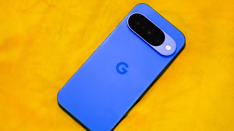 A Google Pixel phone with a blue back on a yellow surface