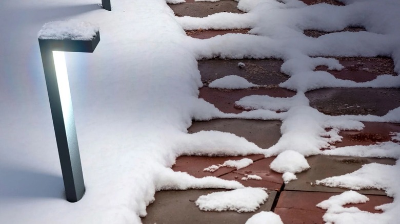 One unit of the Atomi Smart Wi-Fi Platea Outdoor Pathway Lights installed outdoors, illuminating a snowy walkway.