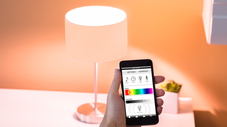 A person controlling a smart lamp through an app on their smartphone.