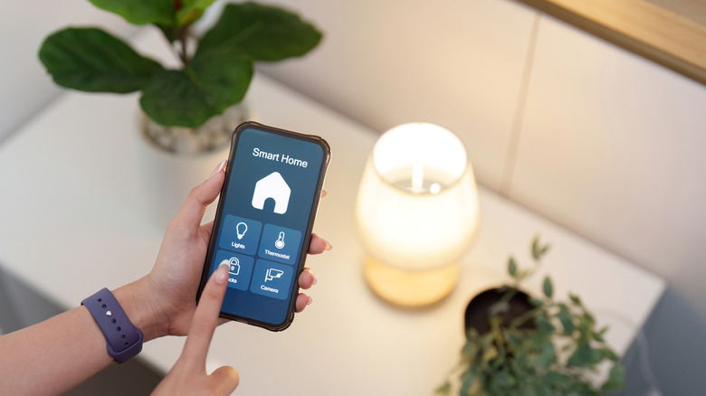 A person using their smartphone to control a table lamp