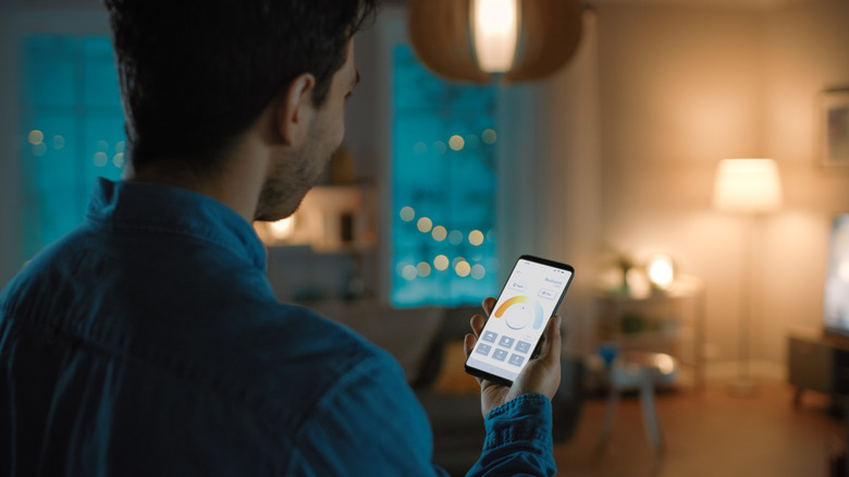 A person controlling the lights in a house with a smartphone