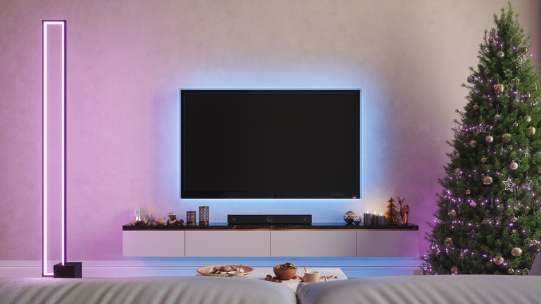 A television with a light behind it in a room with a Christmas tree