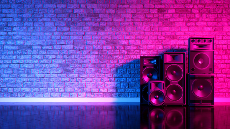 Speakers against a brick wall, lit by pink-purple-blue light